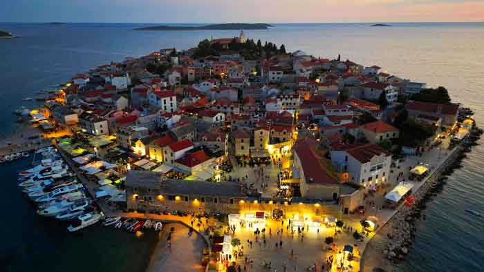 Primošten in der Dämmerung mit beleuchteter Altstadt und Hafen